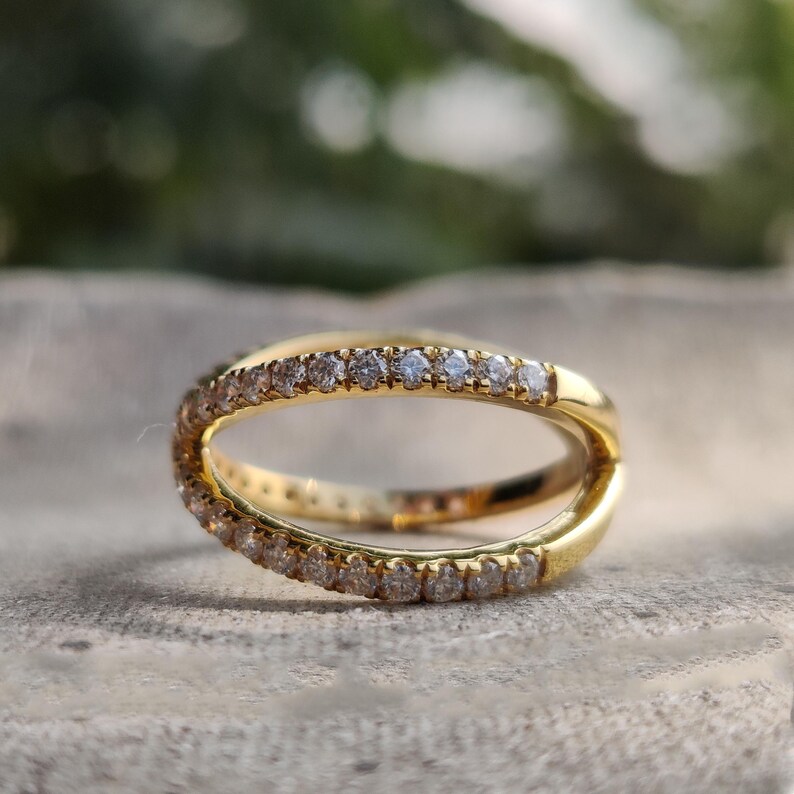 May include: A gold band ring with a row of small diamonds set in the metal. The ring is designed to be worn on the finger with the diamonds facing outwards.