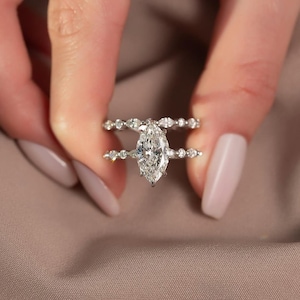 May include: Two diamond rings. The engagement ring features a large, marquise-cut diamond as the centerpiece. The band is adorned with smaller, round diamonds. The second ring is a diamond band with alternating marquise and round diamonds.