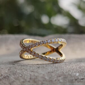 May include: A gold ring with a criss-cross design, set with small clear stones.