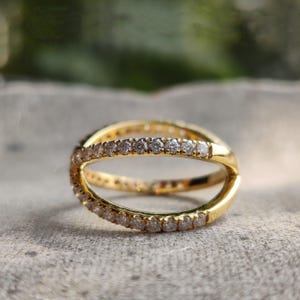 May include: A gold ring with a double band design, each band is set with a row of small, clear diamonds.
