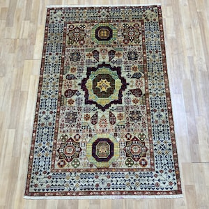 Könnte beinhalten: Rechteckiger Teppich mit einem komplizierten geometrischen Muster. Der Teppich hat ein zentrales Medaillon-Design in den Farbtönen Burgunder, Gold und Grün, umgeben von sich wiederholenden floralen und geometrischen Motiven. Der Rand ist dunkelblau mit einem sich wiederholenden Muster.