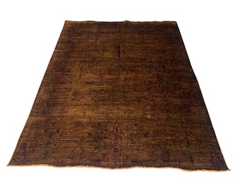 Könnte beinhalten: Ein rechteckiger, brauner Teppich mit detailliertem, gemustertem Design. Der Teppich hat ein abgenutztes Aussehen mit Andeutungen von Rot und Grün. Die Kanten haben einen Fransenrand. Der Teppich ist für ein Wohn- oder Schlafzimmer geeignet.