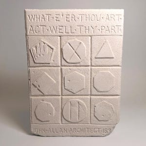 May include: A rectangular light gray stone plaque featuring the engraved text WHAT-E'ER THOU ART ACT WELL THY PART at the top and JOHN ALLAN ARCHITECT 189 at the bottom. The center contains a grid of nine squares with various geometric shapes and symbols.