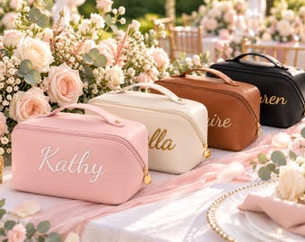 May include: A set of four rectangular cosmetic bags with top handles and gold-toned zipper pulls. The bags are pink, cream, brown, and black, each featuring a name embroidered in cursive script: Kathy, Bella, Claire, and Lauren.