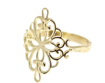 Könnte beinhalten: Ein goldfarbener Ring mit einem großen, vertikalen, durchbrochenen Filigran-Mittelstück mit symmetrischen, wirbelnden und geschlungenen Metallmustern. Die Ringschiene weist eine leicht gehämmerte oder strukturierte Oberfläche auf.