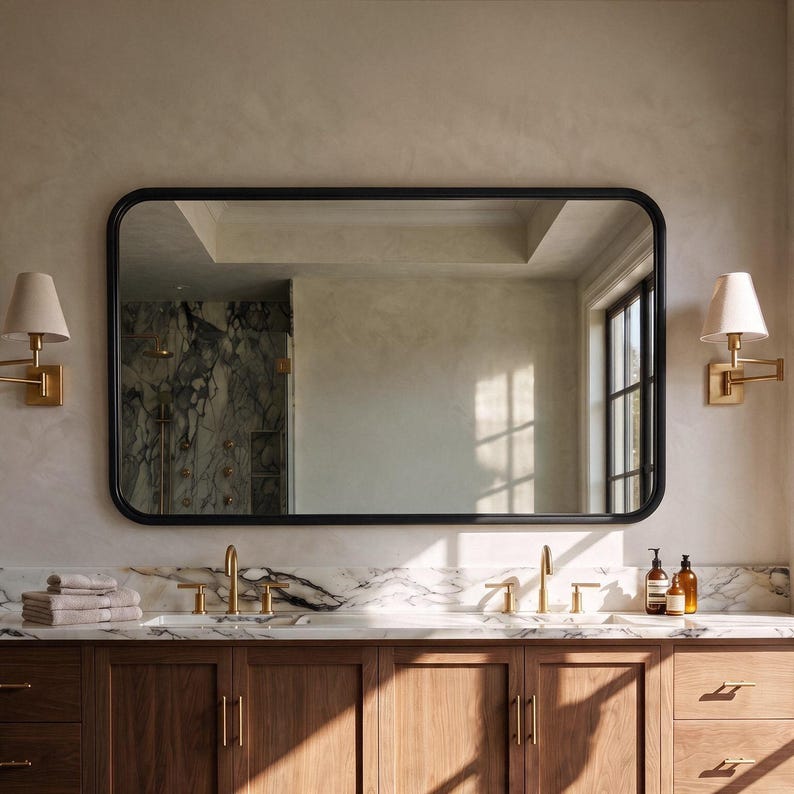 A bold matte black rectangle mirror with rounded corners creating a sharp, minimalist contrast in a modern bathroom.