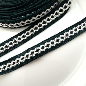 May include: Dark green ribbon featuring a white diamond pattern. The ribbon is tightly woven and appears durable. A section is rolled, with the rest laid flat, displaying the repeating design. The ribbon would be suitable for various craft projects.