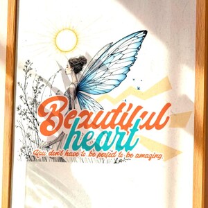 Può includere: Una stampa artistica incorniciata con una cornice in legno. L'opera presenta un disegno di ala di farfalla con le parole "Beautiful heart" in arancione e verde acqua. Un vaso di vetro trasparente con vegetazione è posto accanto alla stampa su un tavolo intrecciato.