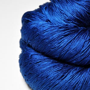 May include: A vibrant, deep royal blue skein of yarn with a distinct sheen and smooth texture. The fibers are tightly twisted together, creating a dense, rounded bundle that reflects light across its surface, highlighting the rich blue color.