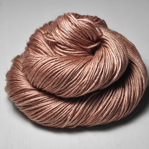 May include: A skein of soft, light brown yarn. The yarn is made of a smooth, silky fiber and is perfect for knitting or crocheting.