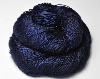 May include: A skein of dark blue yarn with subtle color variations. The yarn appears to be tightly wound, with visible strands creating a textured surface. The color shifts from deep navy to lighter shades of blue.