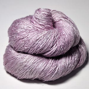 May include: A skein of soft, light purple silk yarn with a subtle sheen. The yarn is loosely wound and has a delicate, airy texture.