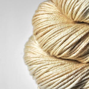 May include: A skein of cream-coloured yarn, wound into a ball shape.