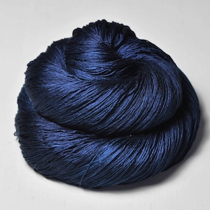 May include: A skein of dark blue yarn, tightly wound and textured. The yarn has a slight sheen, suggesting a silk or similar fiber. The color is a deep, rich blue, with subtle variations in tone. The yarn is likely for knitting or crochet projects.