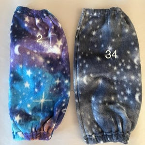 Pode incluir: Dois pares de aquecedores de pernas de l&atilde; polar com estampa de gal&aacute;xia. Um par &eacute; azul, roxo e branco com o n&uacute;mero "2" nele. O outro par &eacute; cinza com o n&uacute;mero "34" nele.