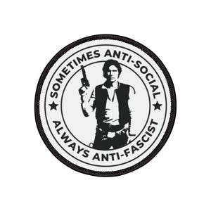 May include: A circular black and white patch featuring a silhouette of a man holding a gun. The text around the image reads "Sometimes Anti-Social, Always Anti-Fascist."