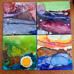 May include: Four square abstract paintings with a variety of colours and shapes. The paintings are in a green, blue, purple, and orange colour scheme. The paintings are all different sizes and shapes.