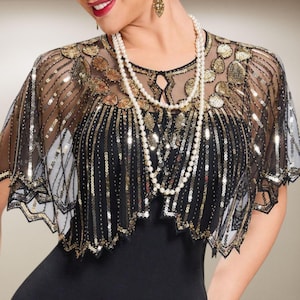 May include: A black sequined capelet with gold accents and a scalloped hem. The capelet is worn over a black dress and paired with a pearl necklace. The capelet features a sheer overlay with gold sequin embellishments, creating a glamorous look.