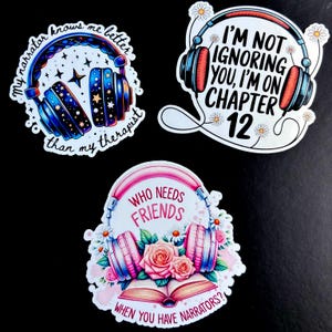 May include: Three colorful stickers with headphones and text. The first sticker has a blue and purple galaxy design with the text "My narrator knows me better than my therapist". The second sticker has red headphones with the text "I'm not ignoring you, I'm on chapter 12". The third sticker has pink headphones with a book and flowers and the text "Who needs friends when you have narrators?".