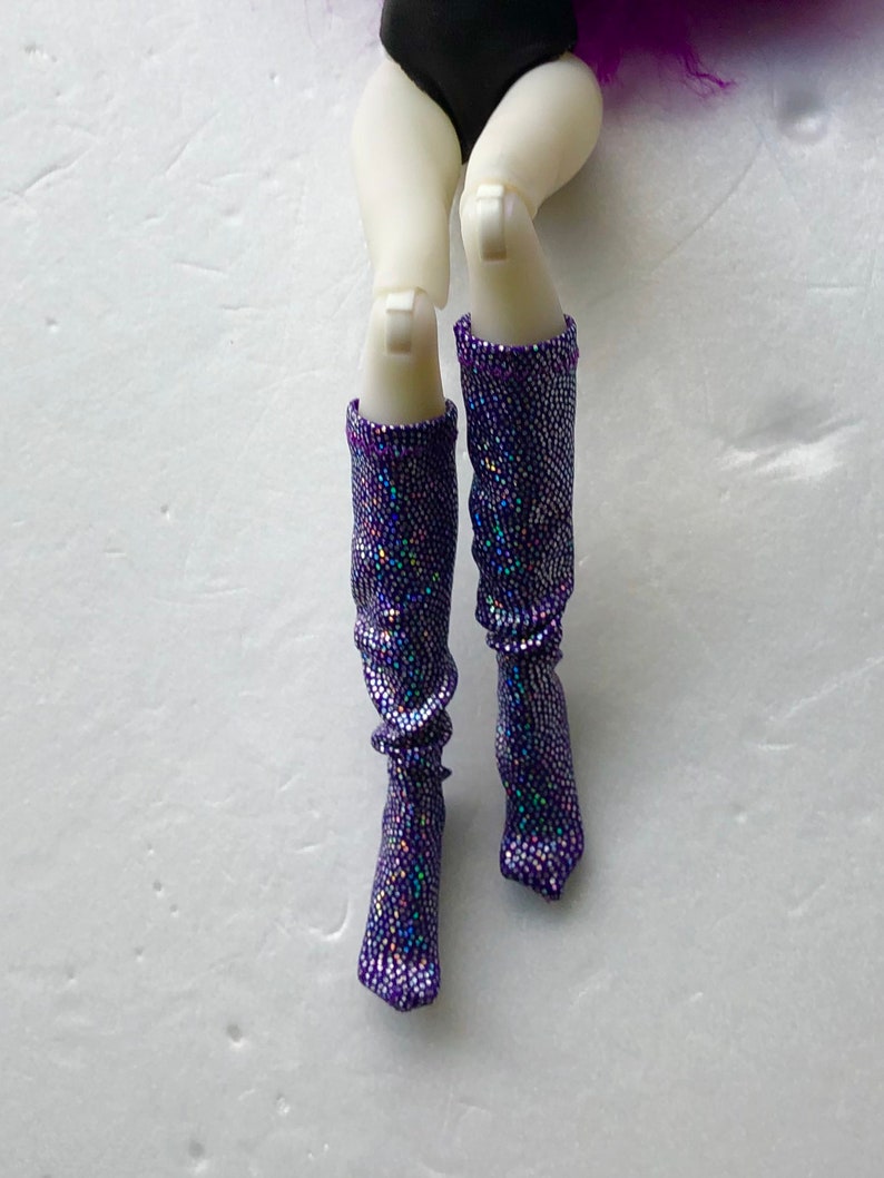May include: A pair of purple sparkly knee-high boots with iridescent glitter.