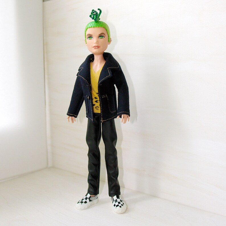 May include: A doll with green hair styled in a mohawk, wearing a black jacket with a yellow shirt underneath, black trousers, and black and white checkered shoes.