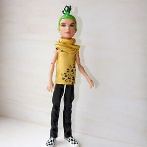 May include: A doll with green hair and a yellow shirt with black markings. The doll is wearing black trousers and black and white shoes.