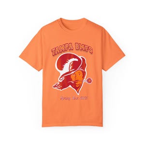 May include: Orange t-shirt with a red and white Tampa Bay Buccaneers logo and the text "Tampa BMFS Spring Tour 2023".