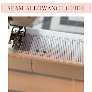 May include: A white seam allowance guide sticker applied to a sewing machine bed. The guide features vertical lines in red, blue, green, and black, with fractional inch markings printed above the lines. The text SEAM ALLOWANCE GUIDE is visible.