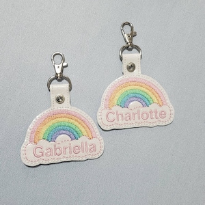 May include: Two rainbow-themed keychains with personalized names. The keychain on the left says "Gabriella" and the keychain on the right says "Charlotte".