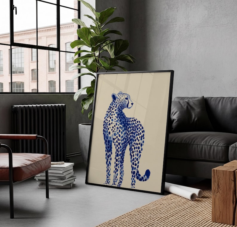 May include: A framed wall art print featuring a stylized blue cheetah with a spotted pattern on a solid beige background. The cheetah is depicted in a standing position, facing toward the right side of the frame with its head turned slightly.