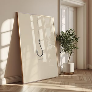 May include: A large rectangular framed wall art piece featuring a minimalist illustration of a single black fishing hook suspended by a thin line against a solid, light beige background. The frame is thin and metallic, showcasing a clean design.