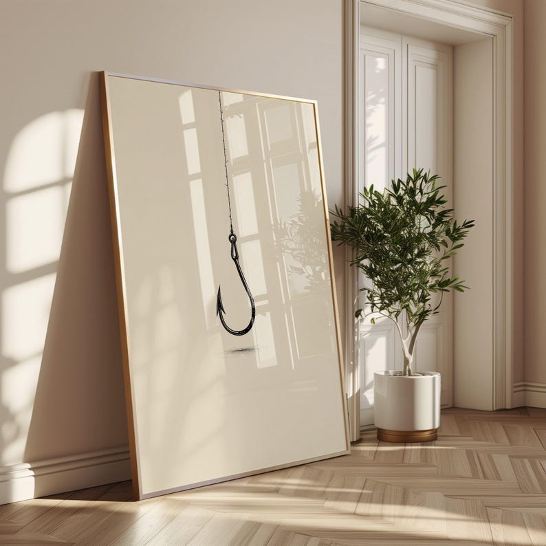May include: A large rectangular framed wall art piece featuring a minimalist illustration of a single black fishing hook suspended by a thin line against a solid, light beige background. The frame is thin and metallic, showcasing a clean design.