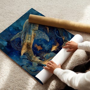 May include: A blue and gold art print featuring a whale shark and goldfish. The print is rolled up with a white and brown tube. The art print is on a white carpet.