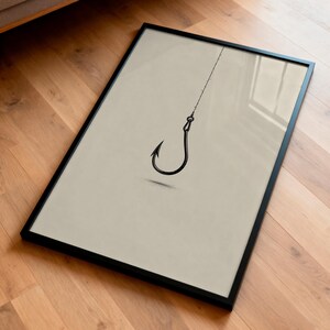 May include: A framed wall art print featuring a minimalist black line drawing of a single fishing hook suspended from a thin vertical line, set against a solid light beige background within a thin black rectangular frame.