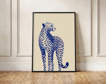 May include: A framed wall art print featuring a stylized illustration of a cheetah. The cheetah is rendered in deep blue watercolor-style spots against a solid light beige background. The artwork is enclosed in a thin, simple black frame.