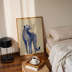 May include: A rectangular framed wall art print featuring a blue and white watercolor-style illustration of a standing cheetah. The cheetah is depicted in profile, facing right, with detailed blue spots against a light beige background.