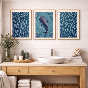 Pode incluir: Tr&ecirc;s quadros de parede emoldurados com um tubar&atilde;o-baleia azul e branco a nadar entre um grande cardume de peixes. A impress&atilde;o central mostra o tubar&atilde;o-baleia, enquanto as duas laterais exibem um padr&atilde;o denso de peixes a nadar.