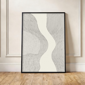 May include: Abstract black and white art print in a black frame. The artwork features a flowing, organic design with a central cream-colored shape and surrounding areas filled with lines and dots. The print is displayed on a wooden floor.
