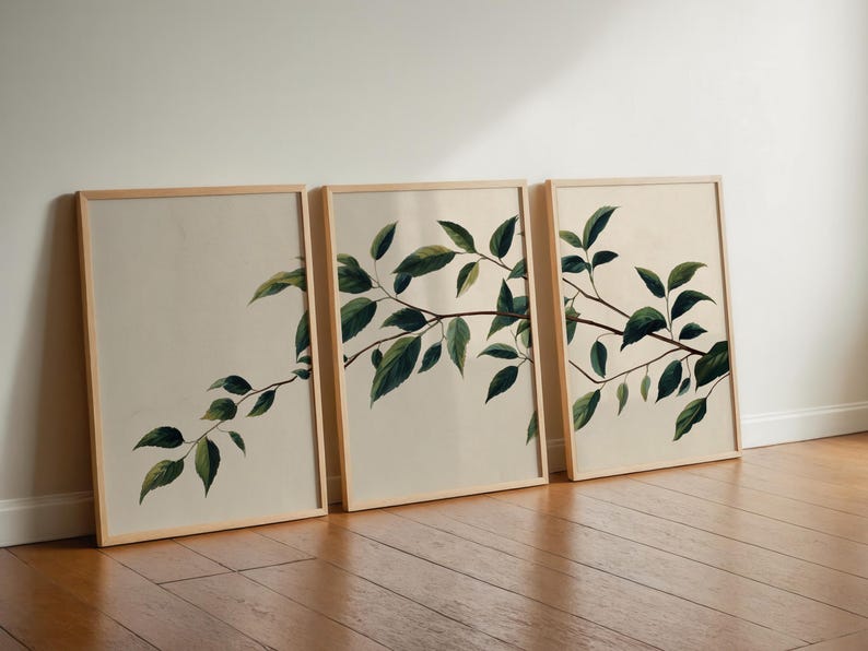 May include: A set of three rectangular wall art prints in light wood frames. Each print features a botanical illustration of a single tree branch with dark green leaves against a solid off-white background, creating a continuous visual flow.