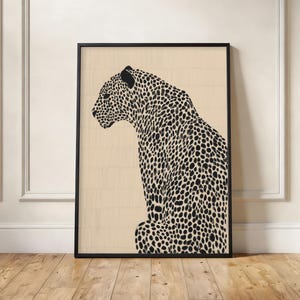 May include: A framed wall art print featuring a black and white illustration of a leopard in profile, facing left. The leopard has a detailed spotted coat pattern and is set against a light beige background with a subtle vertical wood grain texture.
