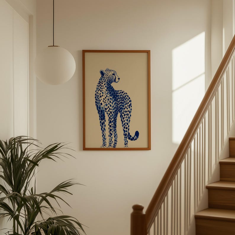 May include: A rectangular wall art print featuring a blue cheetah illustration with dark blue spots on a light beige background, enclosed within a simple wooden frame. The cheetah is depicted in a standing profile position, looking backward.