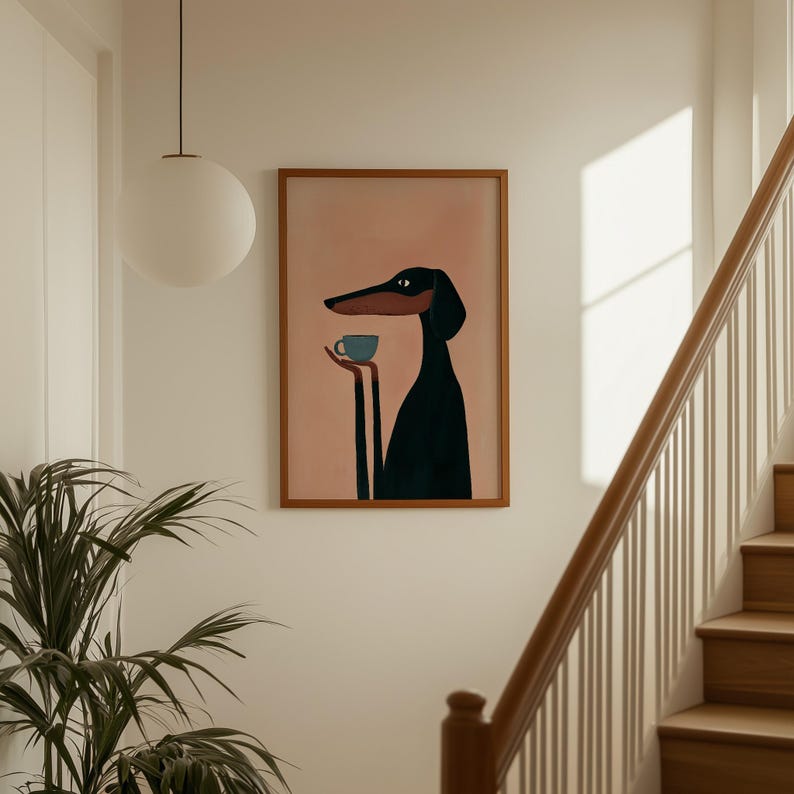 May include: A framed wall art print featuring a stylized illustration of a black and brown dog with long limbs holding a small blue cup. The dog is depicted against a solid muted pink background, enclosed within a simple wooden frame.
