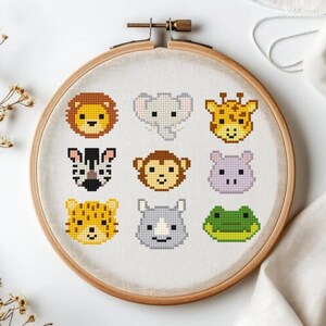 Könnte beinhalten: Ein Kreuzstich-Stickrahmen mit neun verschiedenen Gesichtern von Safari-Tieren. Die Tiere umfassen einen Löwen, einen Elefanten, eine Giraffe, ein Zebra, einen Affen, ein Nilpferd, einen Geparden, ein Nashorn und einen Frosch. Die Tiere sind in verschiedenen Farben gestickt.