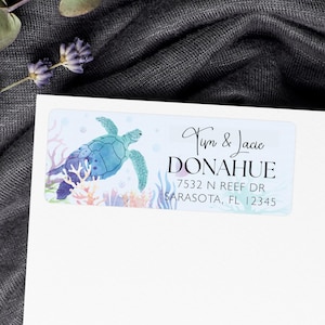 May include: A rectangular label featuring a watercolor sea turtle in shades of blue and teal, surrounded by coral and bubbles. The label includes the names "Tym & Jacie DONAHUE" and an address in Sarasota, FL.