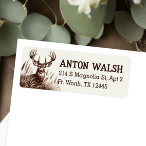 May include: A rectangular label with a deer illustration and the text "ANTON WALSH" in a serif font. The label also includes the address "214 S Magnolia St, Apt 2, Ft. Worth, TX 12445". The deer is depicted in a field of tall grass.