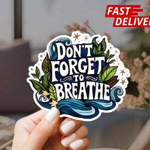 May include: A white sticker with blue and green illustrations of waves and leaves. The sticker says "Don't forget to breathe" in a stylized font.