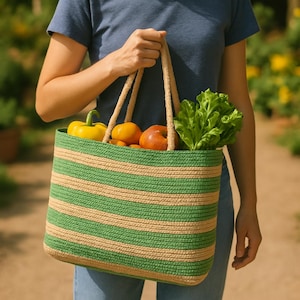 Op de afbeelding: Een groene en beige gestreepte draagtas gevuld met verse producten, waaronder gele paprika's, rode appels en groene sla.