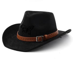 May include: Black cowboy hat with a brown leather band and buckle. A butterfly design is on the front of the hat. The hat has a wide brim and a classic fedora crown.