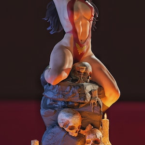 Peut inclure: Figurine d&eacute;taill&eacute;e d'une femme en body rouge avec un embl&egrave;me dor&eacute;, posant les bras au-dessus de la t&ecirc;te. Elle est assise sur une structure rocheuse avec des cr&acirc;nes et des bougies allum&eacute;es. L'ensemble est sombre avec un &eacute;clairage chaleureux.