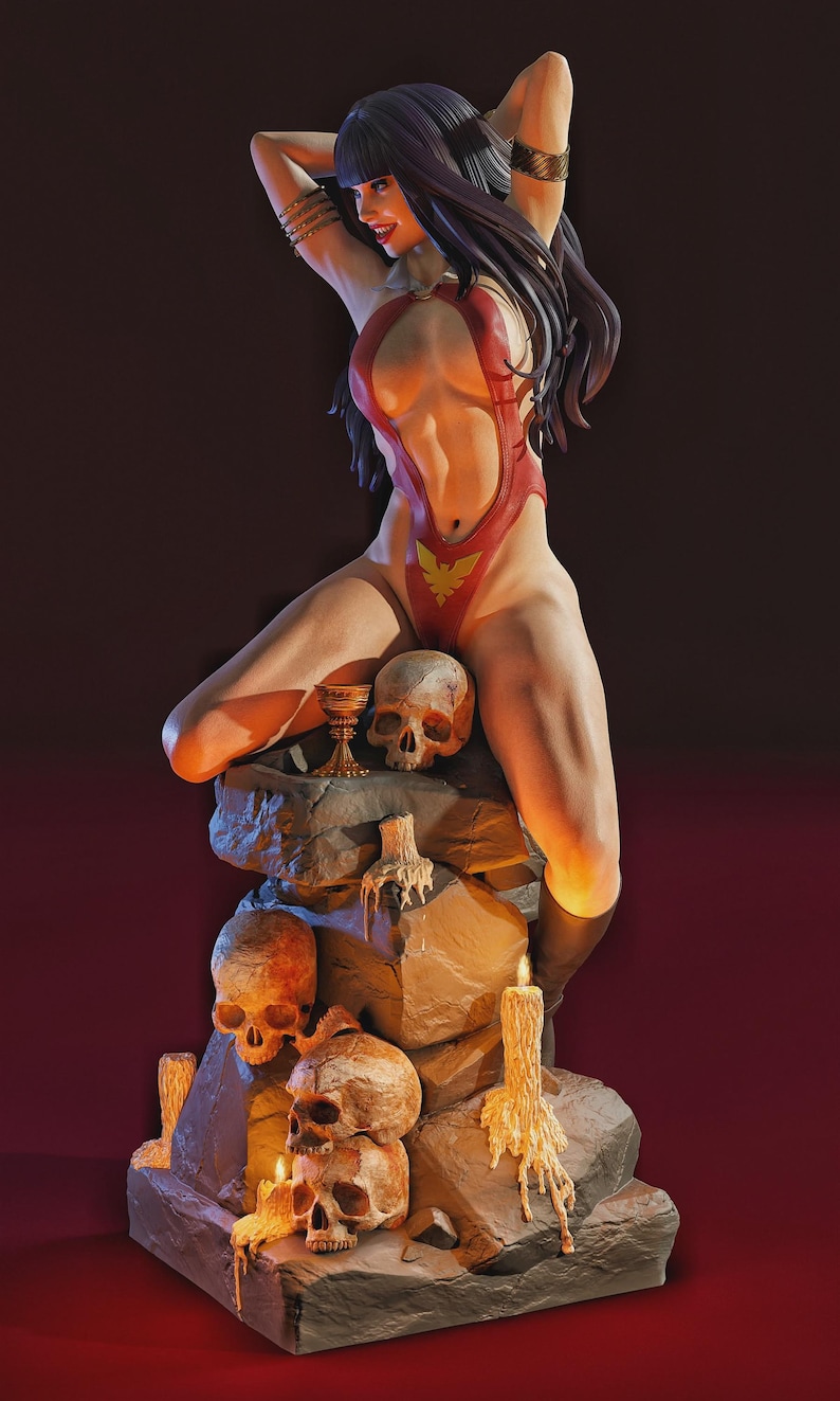 Peut inclure: Figurine d'une femme en body rouge avec un embl&egrave;me de ph&eacute;nix dor&eacute;, pos&eacute;e sur une structure en pierre avec des cr&acirc;nes et des bougies. La figurine a de longs cheveux noirs et est orn&eacute;e de bracelets dor&eacute;s. La sc&egrave;ne est &eacute;clair&eacute;e d'une lumi&egrave;re chaude et dramatique.